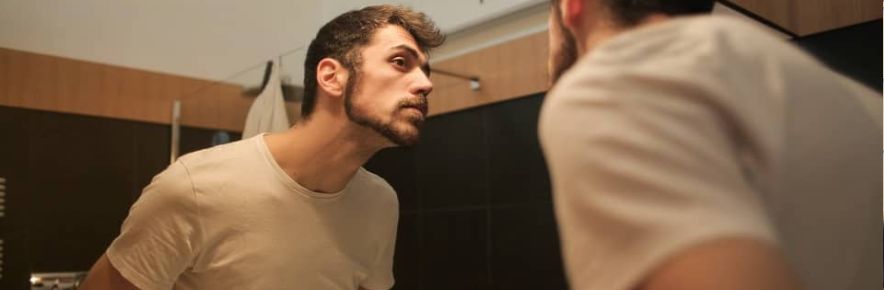 homme qui regarde sa barbe dans le miroir