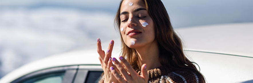 femme qui se met de la crème solaire sur le visage
