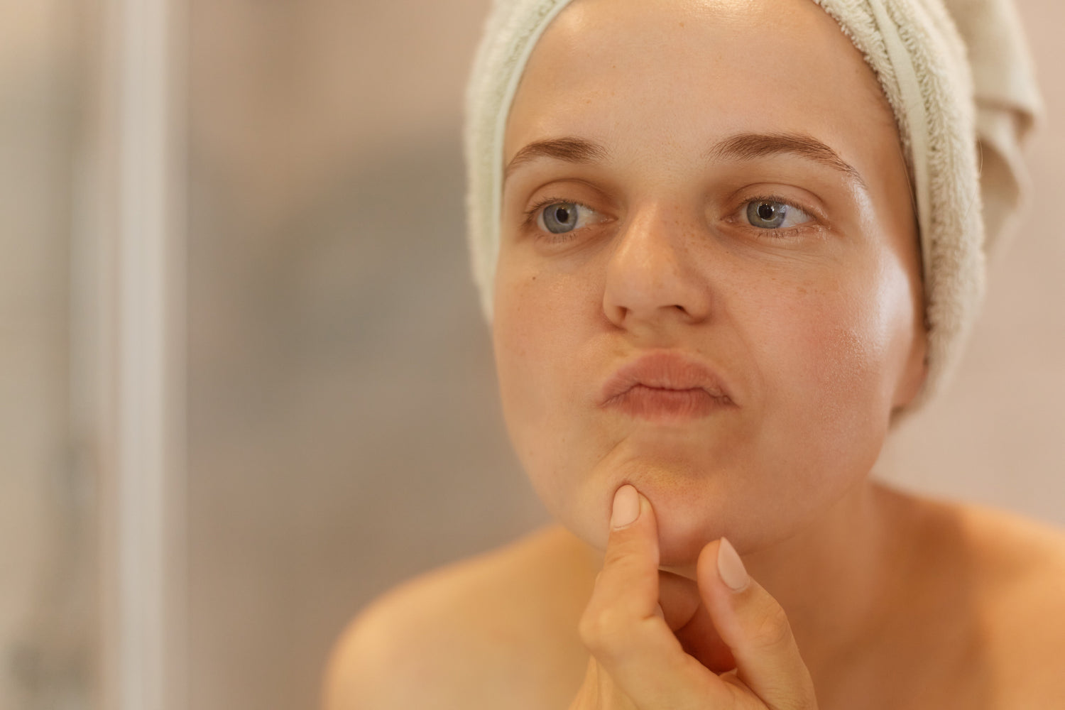 femme regardant sa peau dans un miroir