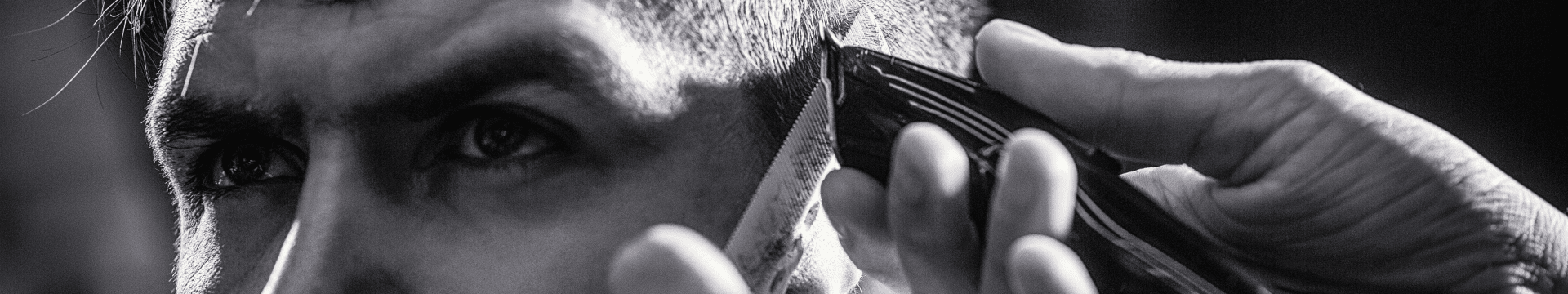 Coiffeur qui fait un dégradé avec une tondeuse à son client